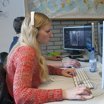 Meisje met rode trui en witte koptelefoon werkt op computer